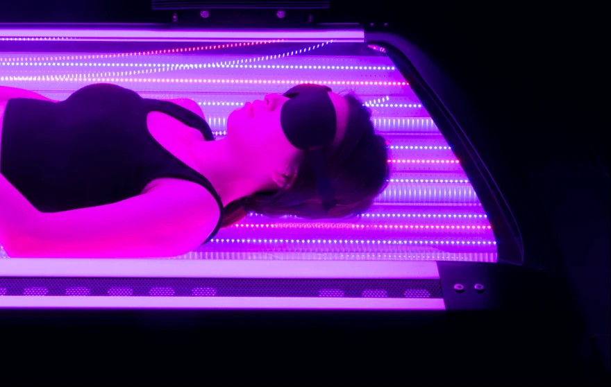 A patient lying inside the Summus Vita light therapy bed wearing eye protection