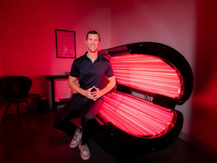 Dr. Josh Axe beside a full-body red light bed