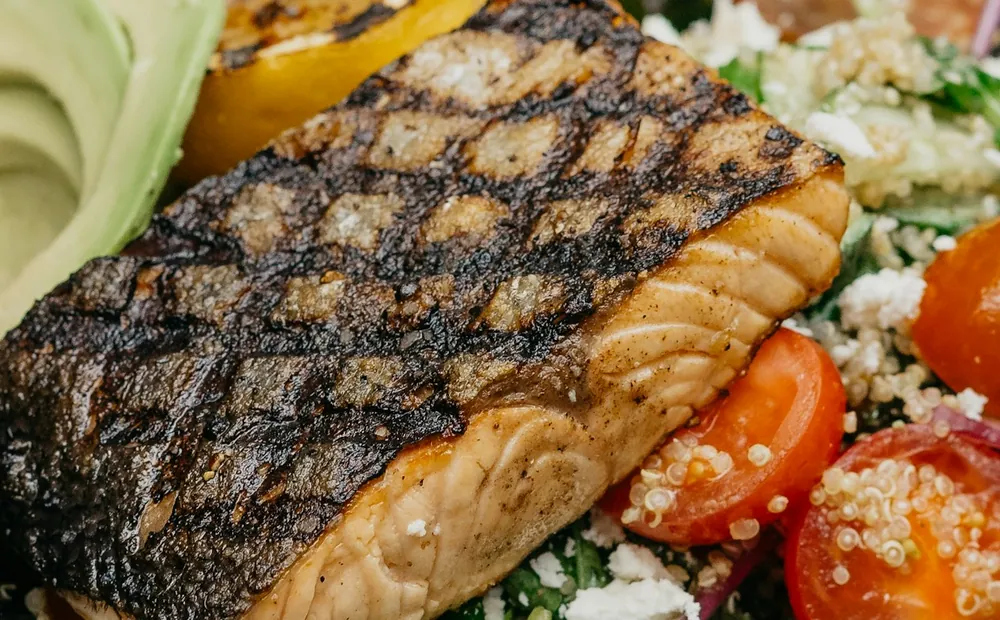 Grilled wild salmon over greens and tomatoes